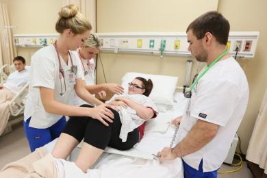 Three Practical Nursing students attending to a patient